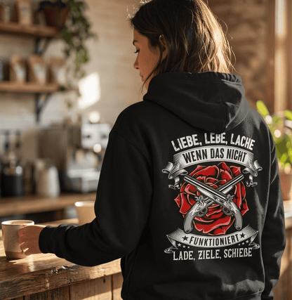 Eine Frau mit einem schwarzen Hoodie steht an der Theke und hält eine Tasse Kaffee