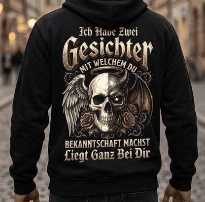 Rückansicht: Mann in schwarzem Hoodie mit humorvollem Engel-und-Teufel-Totenkopf-Motiv