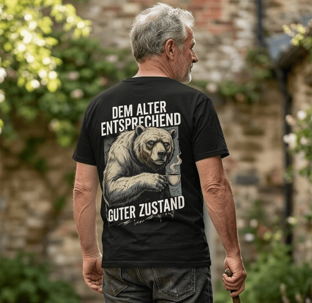 Mann trägt schwarzes T-Shirt Rückansicht mit Spruch Dem Alter entsprechend guter Zustand und Bären-Motiv