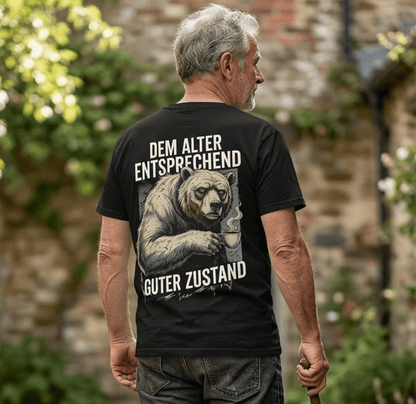 Mann trägt schwarzes T-Shirt Rückansicht mit Spruch Dem Alter entsprechend guter Zustand und Bären-Motiv