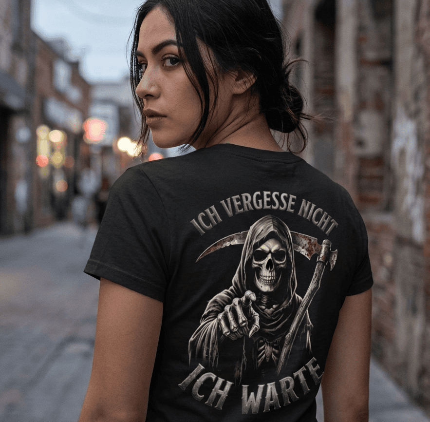 Rückansicht einer Frau in schwarzem T-Shirt mit Spruch Ich vergesse nicht Ich warte und Sensenmann-Motiv